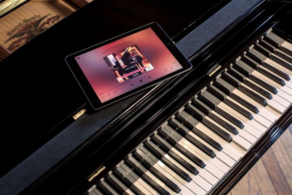 iPad displaying PianoDisc control app resting on glossy black piano