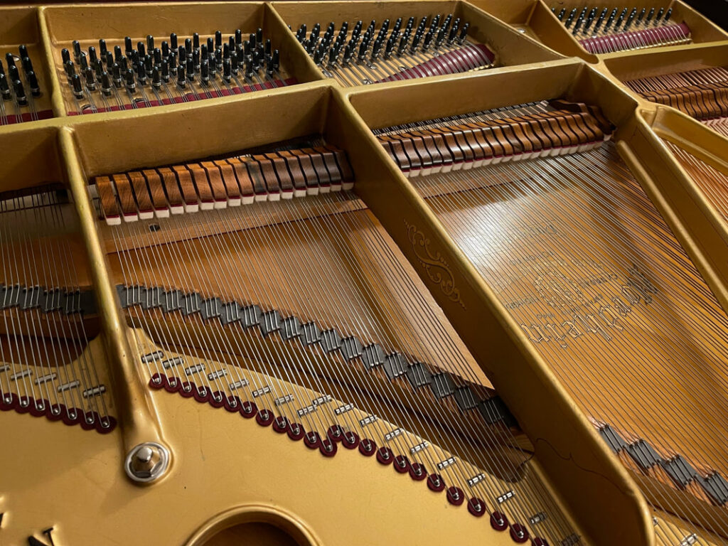 Interior mechanics of vintage tan grand piano during restoration